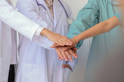 Four Medical Professionals stacking their hands together in a group.