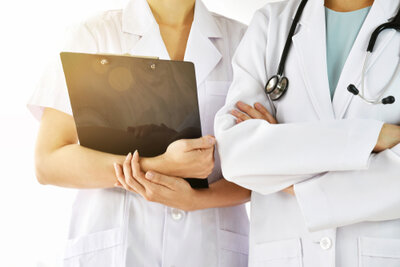 Male and female medical cproviders holding a patient chart.