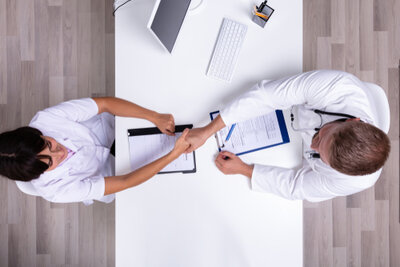 Female shaking hands with male hospital staff member.