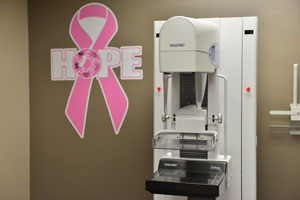 Mammogram Room showing Mammogram Machine and large banner of Breast Cancer ribbon that says HOPE over it.